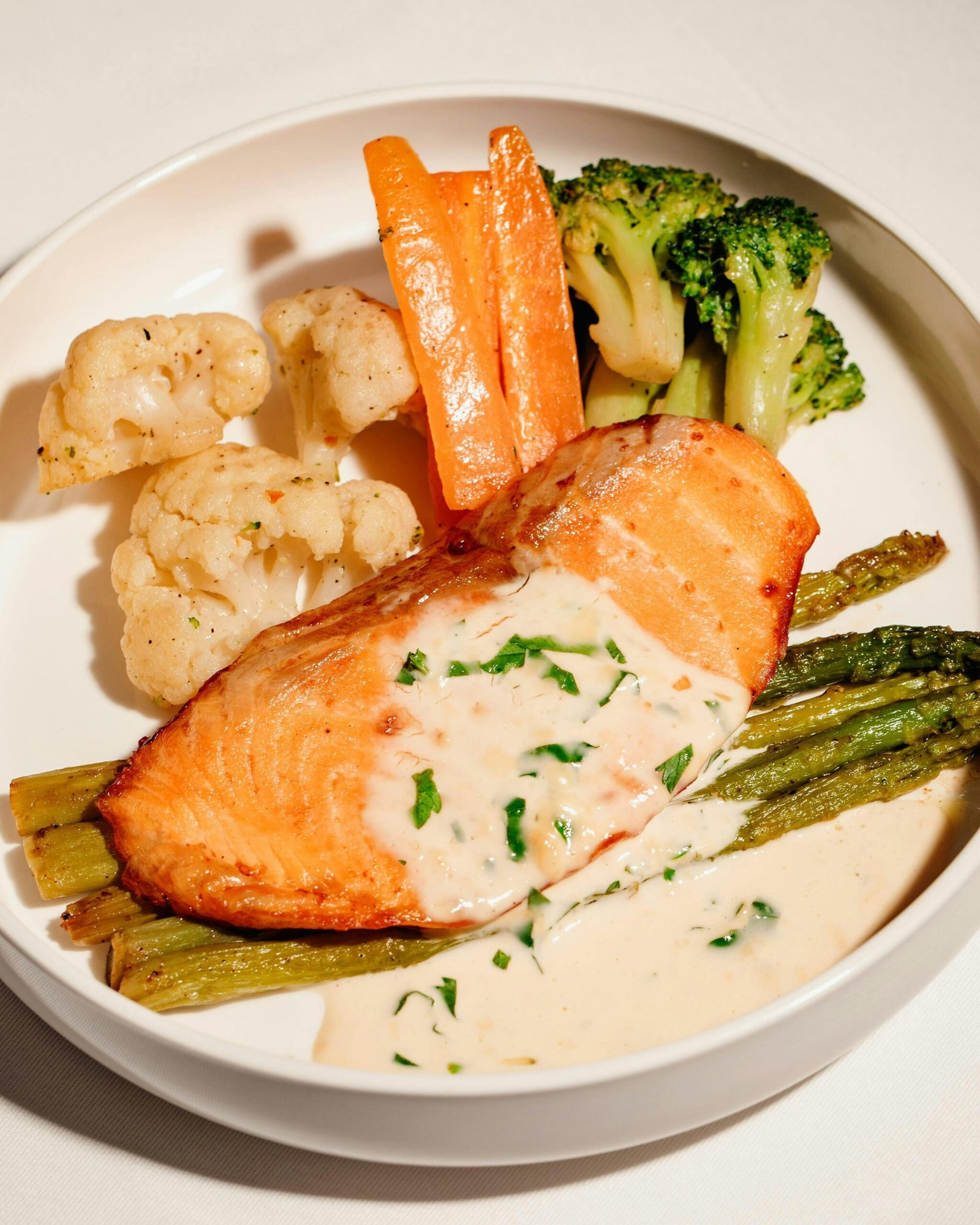 Tasty salmon fillet with creamy sauce, paired with fresh vegetables.